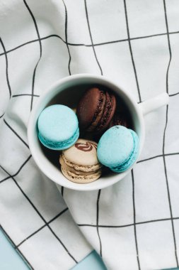 kompozisyon Kupası mavi masada, tatlı tatlı lezzetli macaroons 