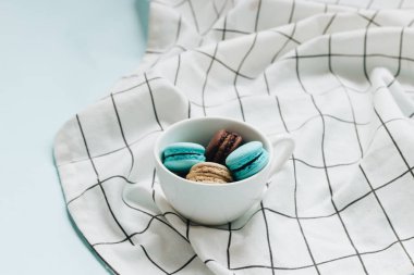 kompozisyon Kupası mavi masada, tatlı tatlı lezzetli macaroons 