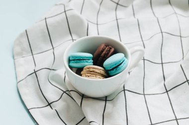 kompozisyon Kupası mavi masada, tatlı tatlı lezzetli macaroons 