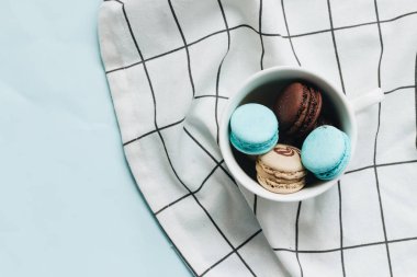kompozisyon Kupası mavi masada, tatlı tatlı lezzetli macaroons 