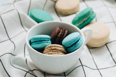 kompozisyon Kupası mavi masada, tatlı tatlı lezzetli macaroons 