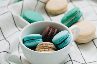 kompozisyon Kupası mavi masada, tatlı tatlı lezzetli macaroons 