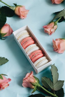 bileşimi lezzetli macaroons ve mavi masada pembe güller