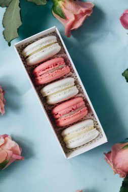 bileşimi lezzetli macaroons ve mavi masada pembe güller