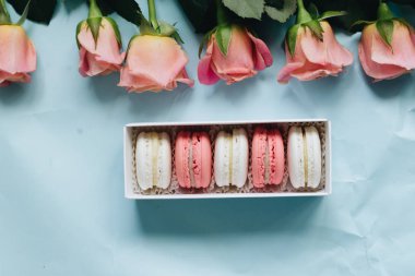 bileşimi lezzetli macaroons ve mavi masada pembe güller