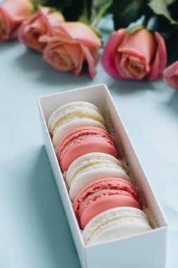 bileşimi lezzetli macaroons ve mavi masada pembe güller