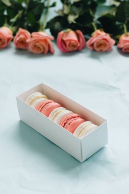 bileşimi lezzetli macaroons ve mavi masada pembe güller