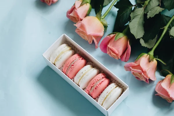 bileşimi lezzetli macaroons ve mavi masada pembe güller