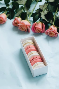 bileşimi lezzetli macaroons ve mavi masada pembe güller