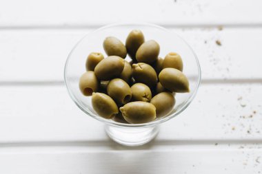 Beyaz arka plan üzerinde küçük cam kase lezzetli yeşil zeytin yığını