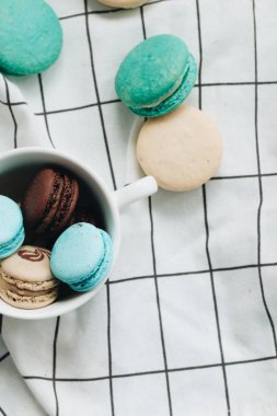 kompozisyon Kupası mavi masada, tatlı tatlı lezzetli macaroons 