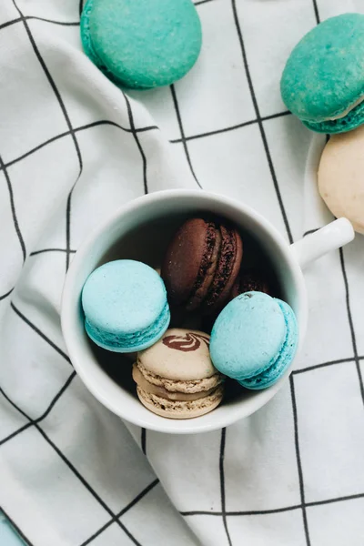 kompozisyon Kupası mavi masada, tatlı tatlı lezzetli macaroons 