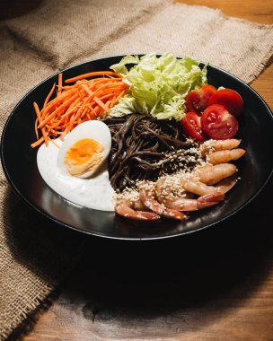 farklı malzemeler, yumurta, karides, domates, havuç, marul, susam ve deniz yosunu siyah plaka, Asya mutfağının lezzetli yemek 