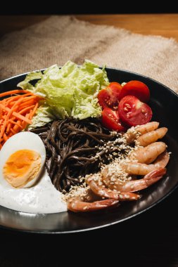 farklı malzemeler, yumurta, karides, domates, havuç, marul, susam ve deniz yosunu siyah plaka, Asya mutfağının lezzetli yemek 