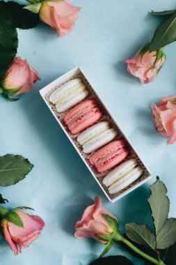 bileşimi lezzetli macaroons ve mavi masada pembe güller
