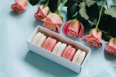 bileşimi lezzetli macaroons ve mavi masada pembe güller