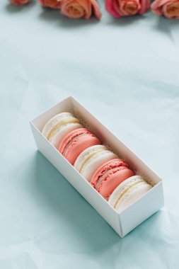 bileşimi lezzetli macaroons ve mavi masada pembe güller