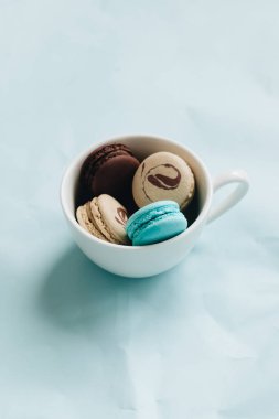 kompozisyon Kupası mavi masada, tatlı tatlı lezzetli macaroons 