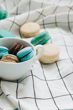kompozisyon Kupası mavi masada, tatlı tatlı lezzetli macaroons 