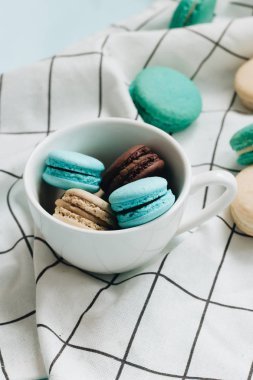 kompozisyon Kupası mavi masada, tatlı tatlı lezzetli macaroons 