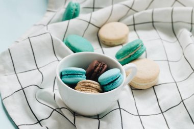kompozisyon Kupası mavi masada, tatlı tatlı lezzetli macaroons 