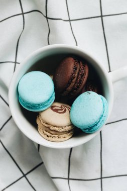 kompozisyon Kupası mavi masada, tatlı tatlı lezzetli macaroons 