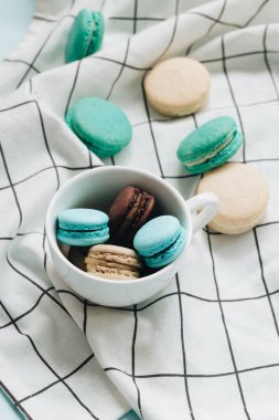 kompozisyon Kupası mavi masada, tatlı tatlı lezzetli macaroons 