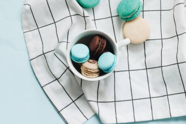 kompozisyon Kupası mavi masada, tatlı tatlı lezzetli macaroons 