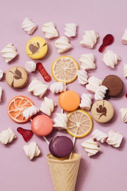 lezzetli tatlı şekerleme ve Lila arka plan üzerinde renkli macaroons ve düz lay