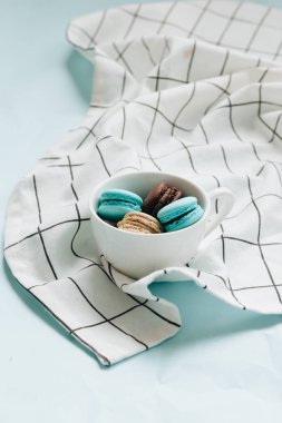 kompozisyon Kupası mavi masada, tatlı tatlı lezzetli macaroons 