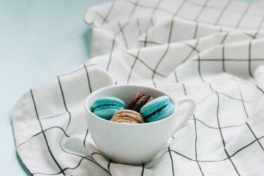 kompozisyon Kupası mavi masada, tatlı tatlı lezzetli macaroons 