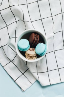 kompozisyon Kupası mavi masada, tatlı tatlı lezzetli macaroons 