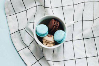 kompozisyon Kupası mavi masada, tatlı tatlı lezzetli macaroons 