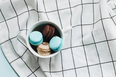 kompozisyon Kupası mavi masada, tatlı tatlı lezzetli macaroons 