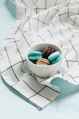 kompozisyon Kupası mavi masada, tatlı tatlı lezzetli macaroons 