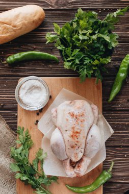 çiğ tavuk ve ahşap masa yemek pişirmek için hazır üzerinde taze otlar 