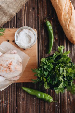 çiğ tavuk ve ahşap masa yemek pişirmek için hazır üzerinde taze otlar 