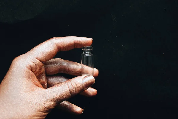 female hand holding small clean bottle on black background