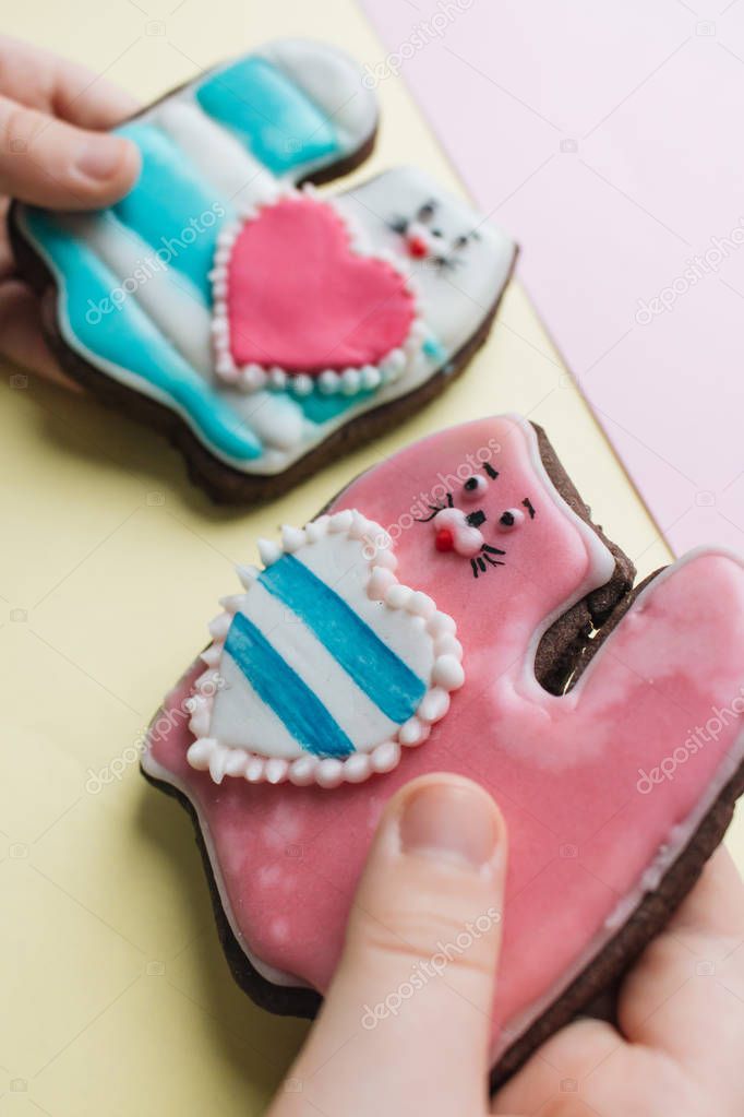 boy's hands holding two cookies in shape of broken heart with glaze