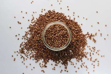 Beyaz arka planda kavanoz ve scatterd çiğ karabuğday