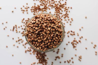 Beyaz arka planda kavanoz ve scatterd çiğ karabuğday