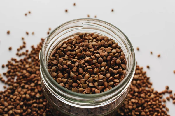 Jar Scatterd Raw Buckwheat White Background — Stock Photo, Image