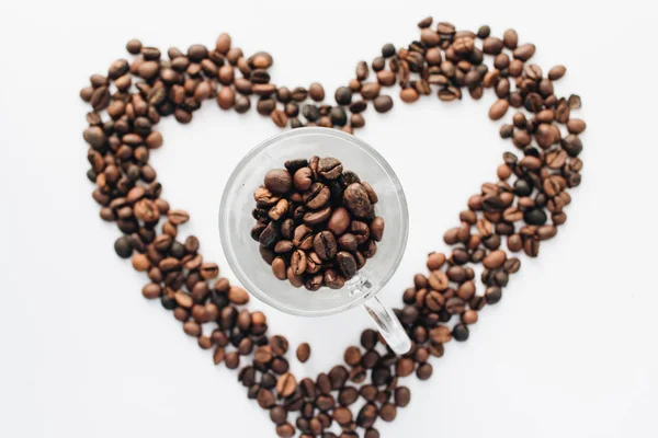 cup and roasted coffee beans, pile in shape of heart