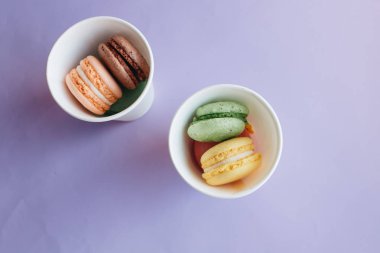 mor arka planda plastik bardakların lezzetli macaroons bileşimi 