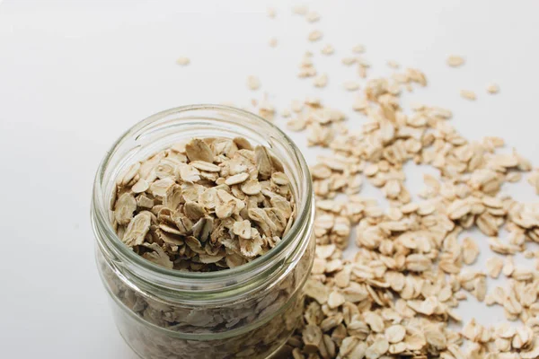 jar with raw oat-flakes on white background