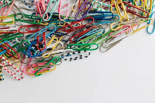 pile of colorful paper clips on white background, flat lay