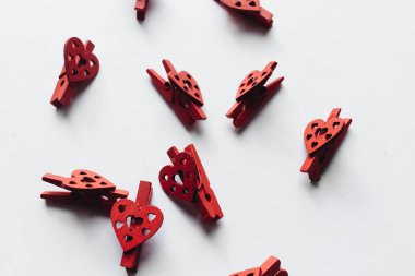 beyaz arka plan üzerinde izole kalp dekorlu dağınık kırmızı giysi mandal yığını