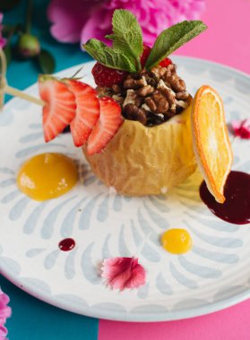 Fındık ve ballı makroyla doldurulmuş fırında elma. Sağlıklı yemek, pembe ve mavi arka plan