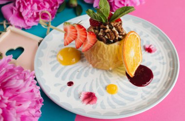 Fındık ve ballı makroyla doldurulmuş fırında elma. Sağlıklı yemek, pembe ve mavi arka plan