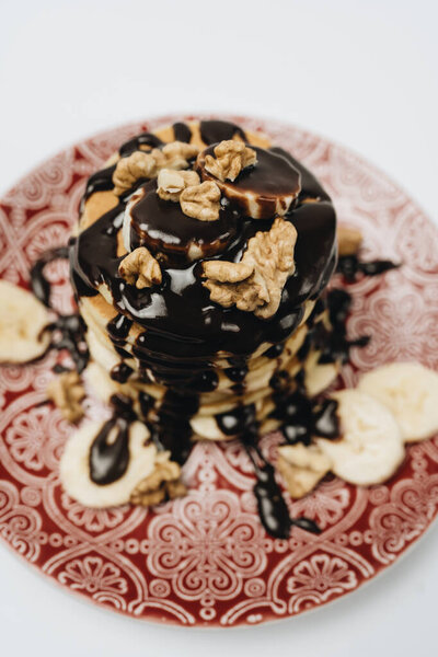 Удивительный и легкий завтрак, стопка вкусных домашних блинов с шоколадом, грецкими орехами и солеными бананами